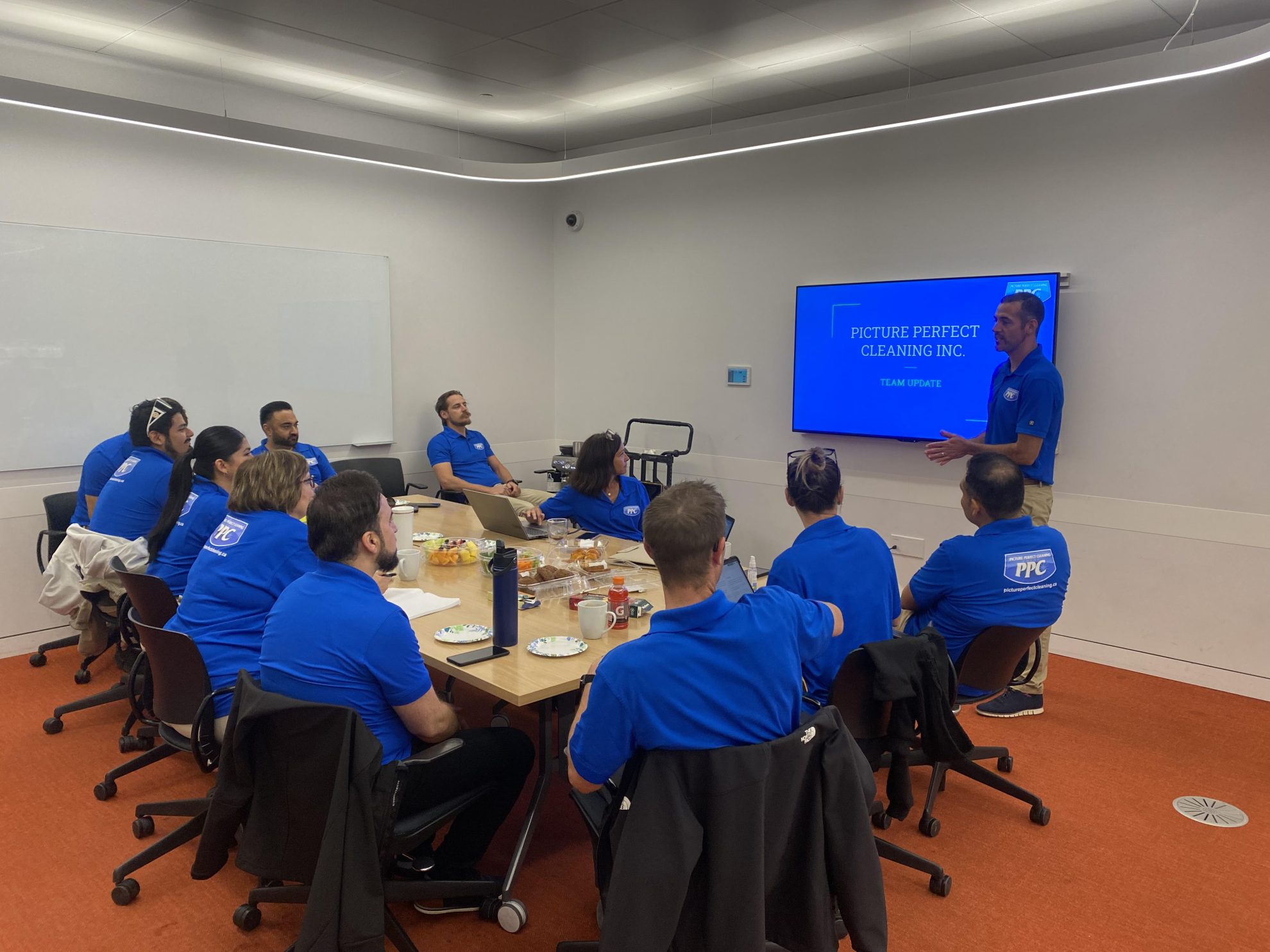 Picture Perfect Cleaning Team Meeting – Employee Health Benefits Picture Perfect Cleaning team gathered in a meeting room, discussing full-time employee health benefits with a presentation on screen.