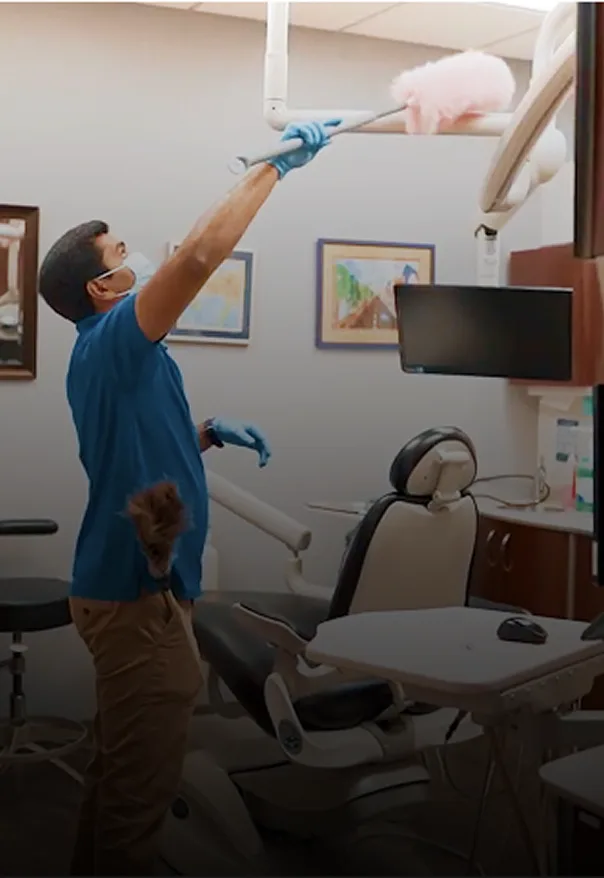 Picture Perfect Cleaning team member dusting an overhead light in a dental treatment room